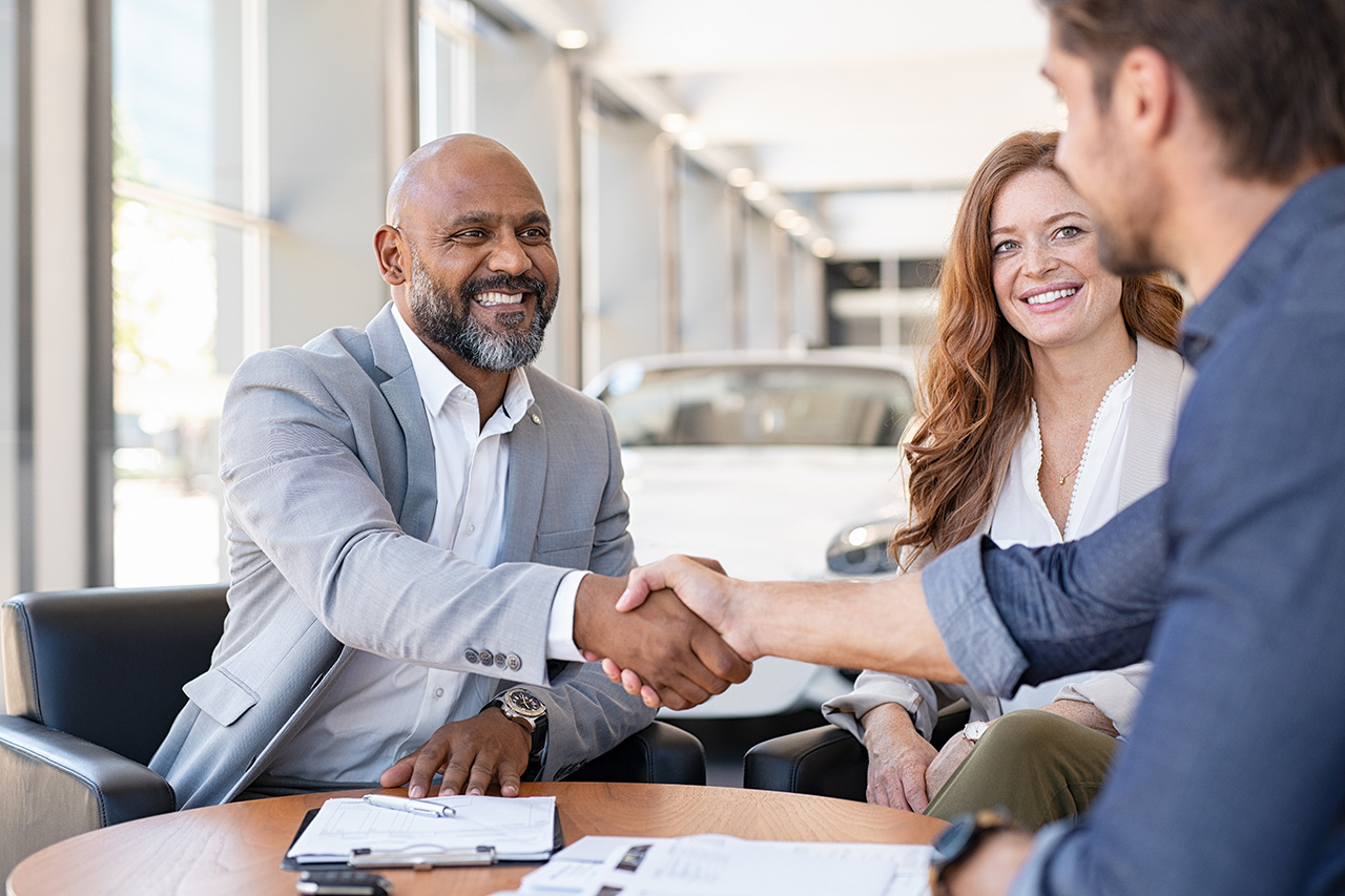 customer and dealer at a desk shaking hands